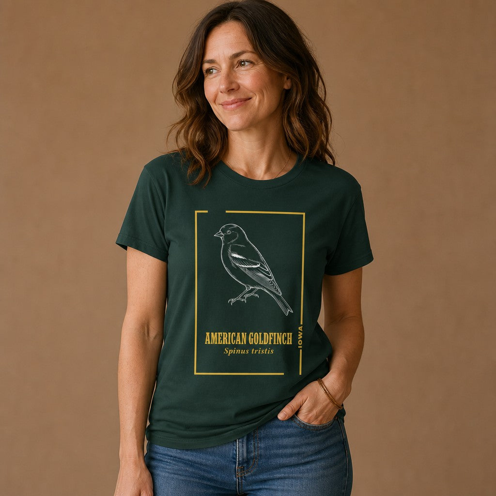Woman wearing a forest green Bella Canvas 3001 t-shirt featuring a hand-drawn vintage line art illustration of an American Goldfinch with golden botanical accents and classic type, ideal for bird lovers and nature journaling enthusiasts, by Crossroads Dandelion