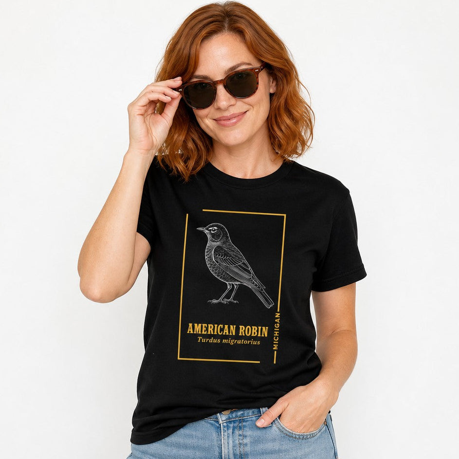 Woman wearing a black Bella Canvas 3001 t-shirt with a vintage line art illustration of an American robin inside a minimalist gold border and elegant typography, inspired by classic field-guide nature prints, birdwatcher and cottagecore lovers apparel, by Crossroads Dandelion