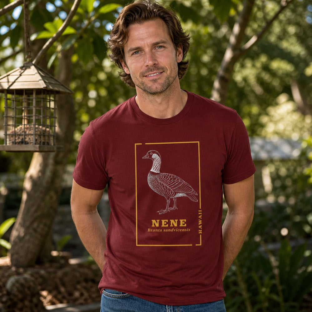 Man in cardinal red Bella Canvas 3001 t-shirt featuring intricate vintage line art of a nene goose with golden botanical borders, celebrating Hawaii’s rare state bird, photographed outdoors in a lush garden, perfect for birdwatchers and nature lovers, by Crossroads Dandelion