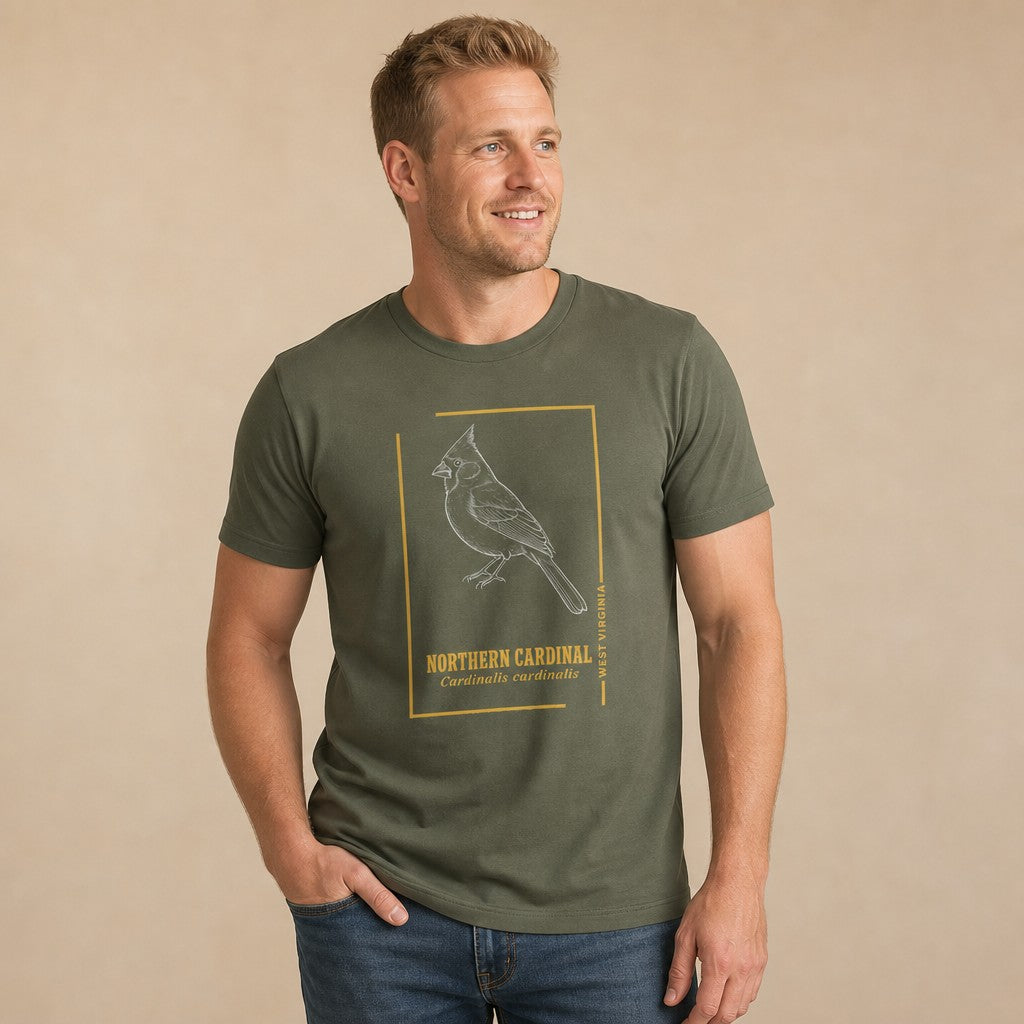 Man wearing a military green Bella Canvas 3001 t-shirt with a vintage-inspired line art illustration of a Northern Cardinal, golden border, and Latin name, perfect for birdwatchers and lovers of classic field guide designs, by Crossroads Dandelion