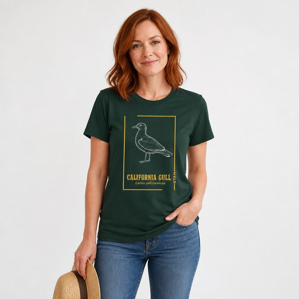 Woman in a forest green Bella Canvas 3001 t-shirt featuring a vintage-style line illustration of the California Gull in chalk-white with golden botanical accents, perfect for birdwatchers and nature art lovers, by Crossroads Dandelion