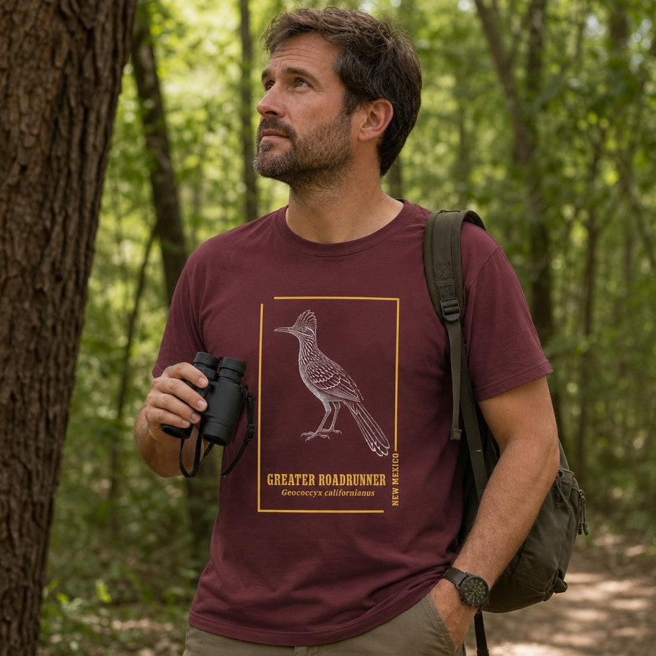 Man in maroon Bella Canvas 3001 t-shirt featuring a vintage-inspired line art illustration of a Greater Roadrunner framed with golden accents, hiking in a sunlit forest, perfect for birdwatchers, nature lovers, and fans of cottagecore aesthetics, by Crossroads Dandelion