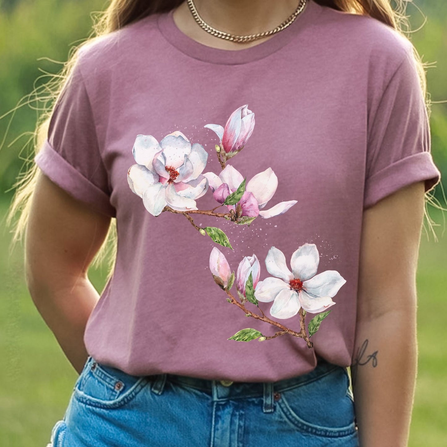 Woman wearing a heather mauve magnolia flower tee with botanical watercolor design  outdoors by Crossroads Dandelion