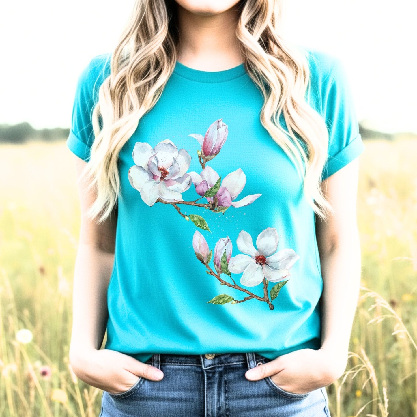Woman wearing a turquoise magnolia flower shirt with watercolor botanical floral art  in a field by Crossroads Dandeli