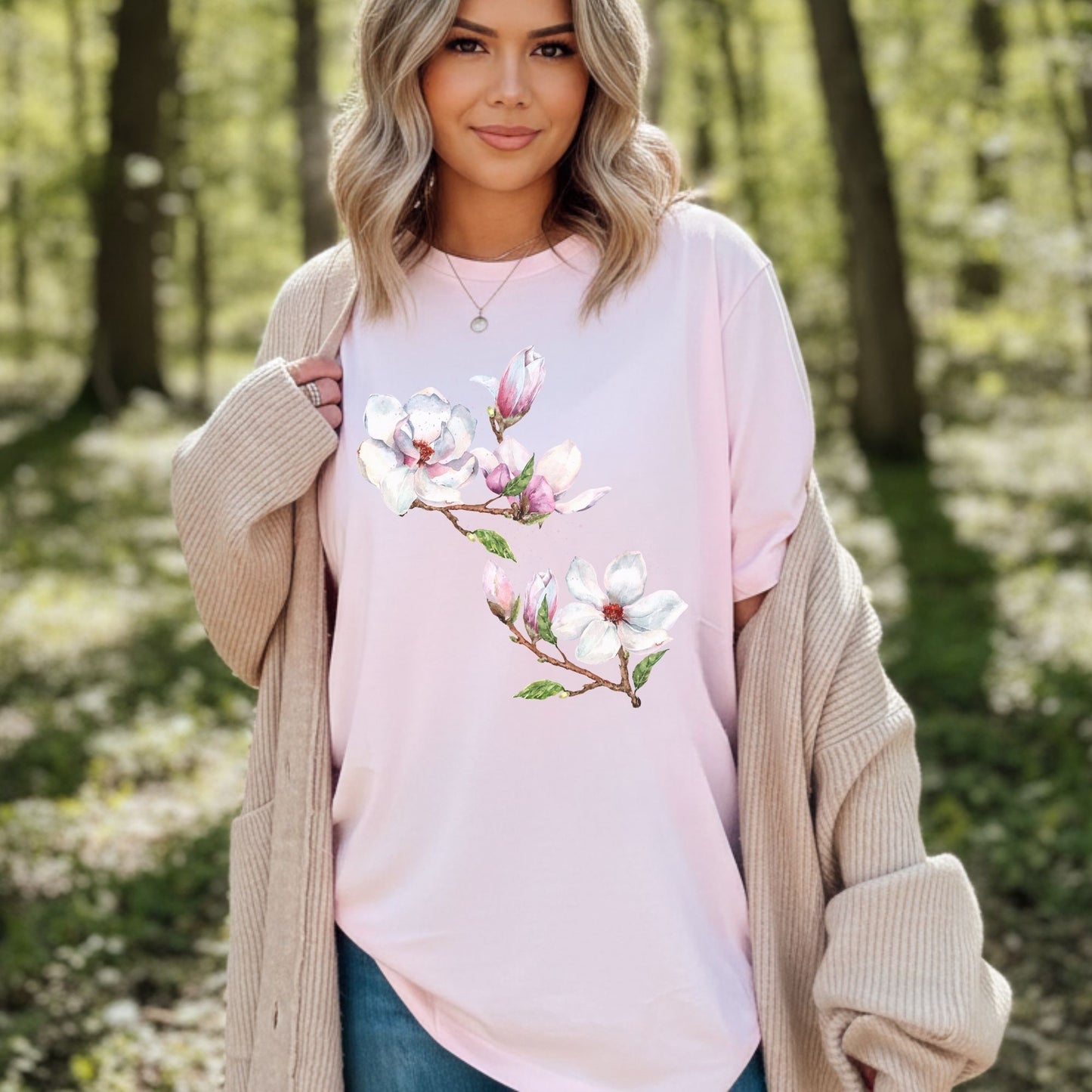 Woman wearing a soft pink vintage magnolia shirt with watercolor botanical floral art  in a forest setting by Crossroads Dandelion

