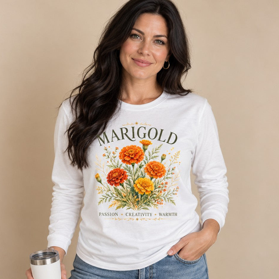 Woman wearing white Bella Canvas® 3501 long sleeve featuring vintage botanical marigold flower illustration with gold flourishes, elegant MARIGOLD text and inspiration words, floral boho style for creative nature lovers, by Crossroads Dandelion