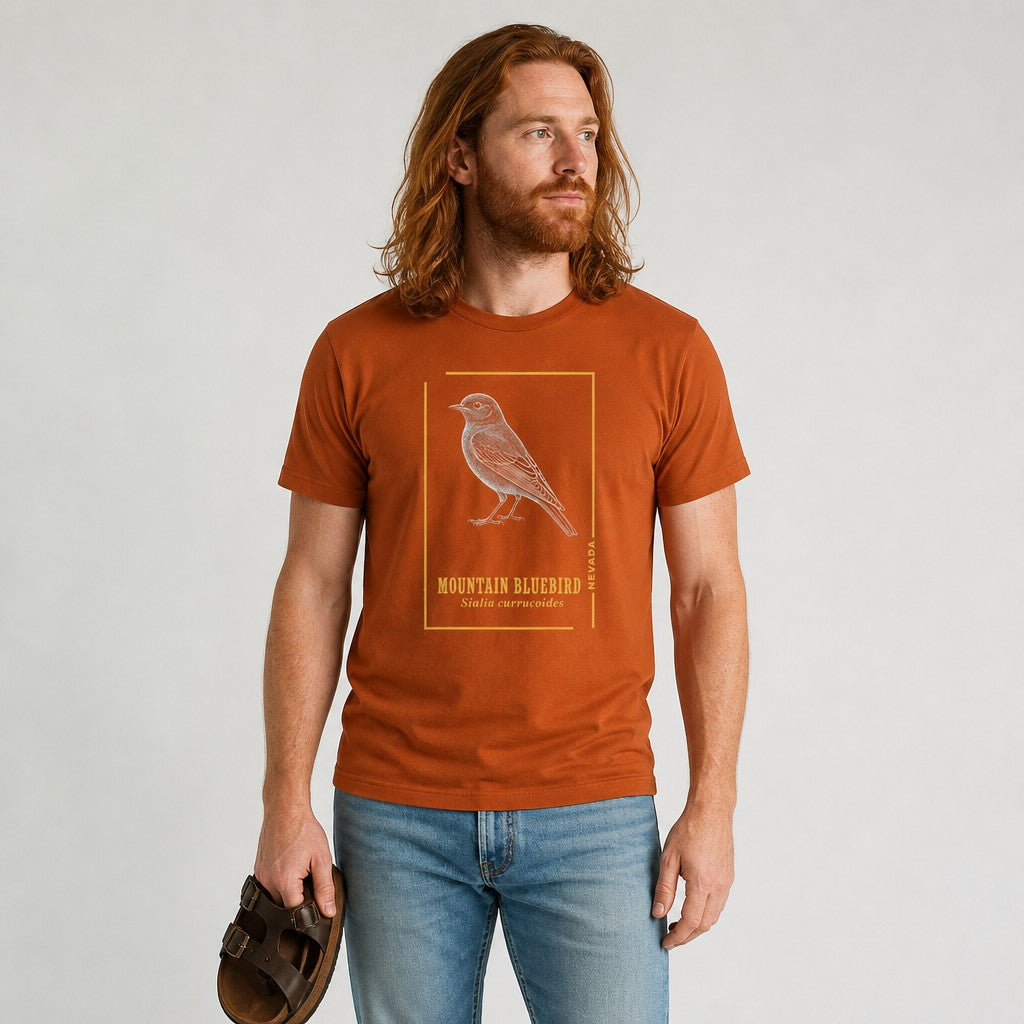 Man wearing autumn-colored Bella Canvas 3001 t-shirt featuring a vintage etched mountain bluebird with golden frame, cottagecore style, minimalist field guide aesthetic, perfect for birders and nature lovers, by Crossroads Dandelion