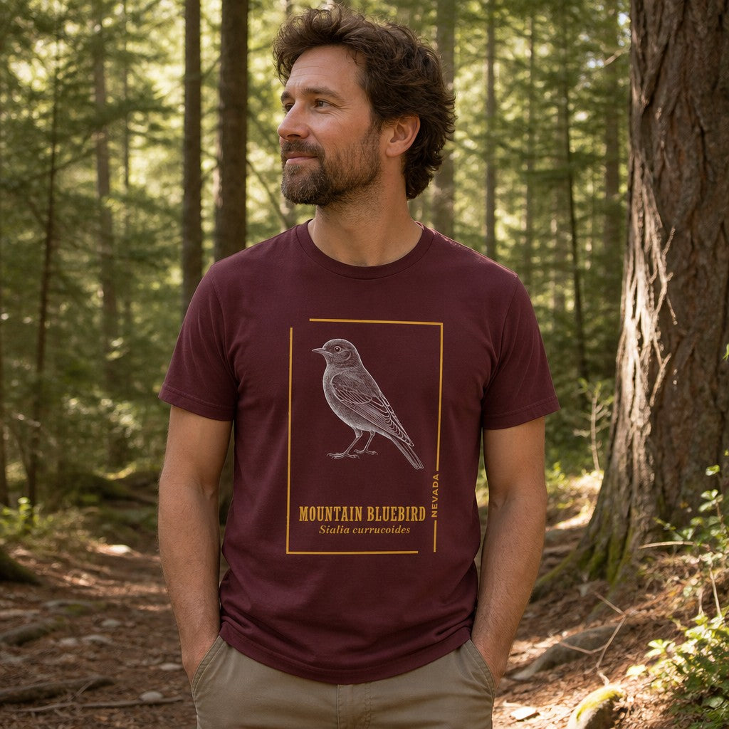 Man wearing maroon Bella Canvas 3001 t-shirt with vintage etched mountain bluebird illustration, framed in gold accents, standing in a sun-dappled forest, cottagecore and birdwatching audience, by Crossroads Dandelion