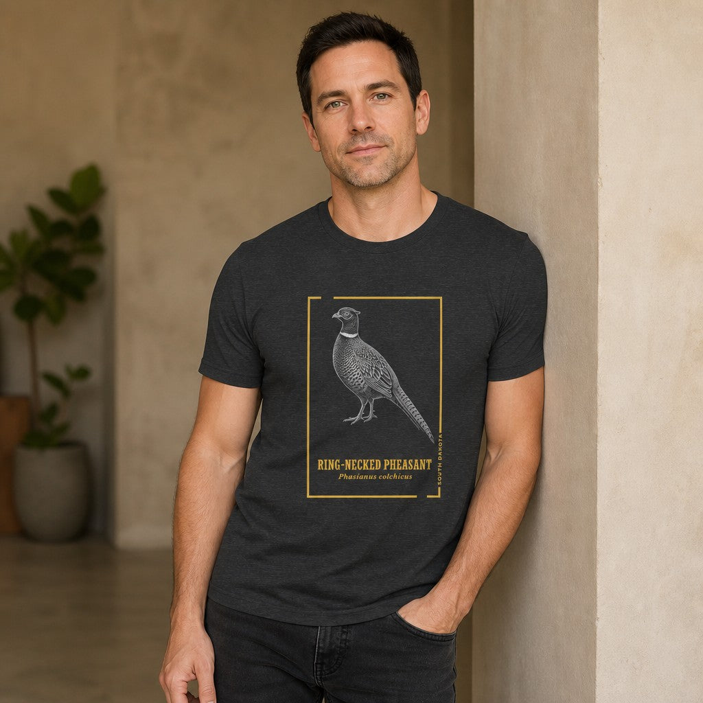 Man wearing dark grey heather Bella Canvas 3001 t-shirt with vintage hand-illustrated ring-necked pheasant design, framed with gold botanical accents and elegant lettering, perfect for birdwatchers, naturalists, and state symbol lovers, photographed in a modern indoor setting, by Crossroads Dandelion