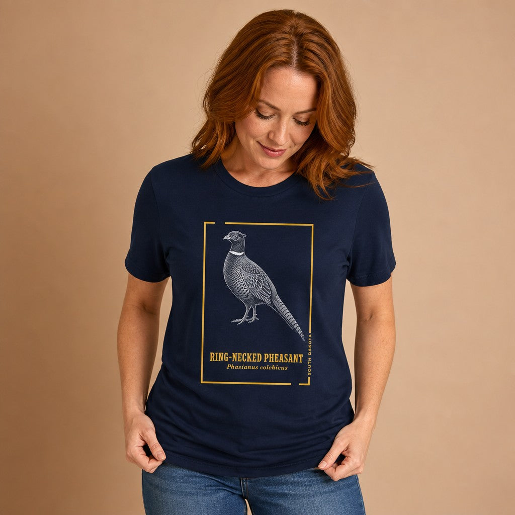 Woman wearing navy Bella Canvas 3001 t-shirt featuring a hand-illustrated vintage engraving of a ring-necked pheasant with golden botanical accents and elegant block lettering, birdwatcher and naturalist gift, vintage style, by Crossroads Dandelion