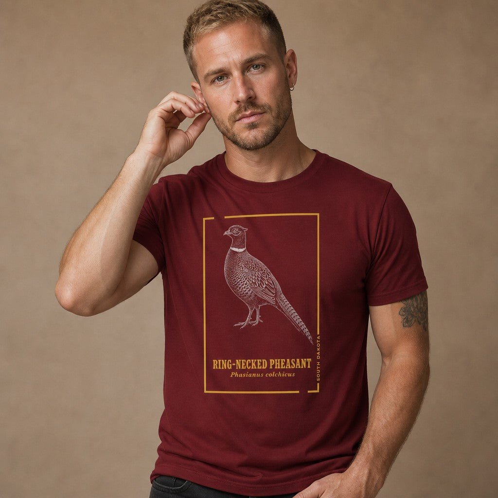 Man wearing a cardinal red Bella Canvas 3001 t-shirt featuring a hand-illustrated ring-necked pheasant in vintage engraving style with golden botanical accents and elegant block lettering, perfect for birdwatchers and naturalists, by Crossroads Dandelion