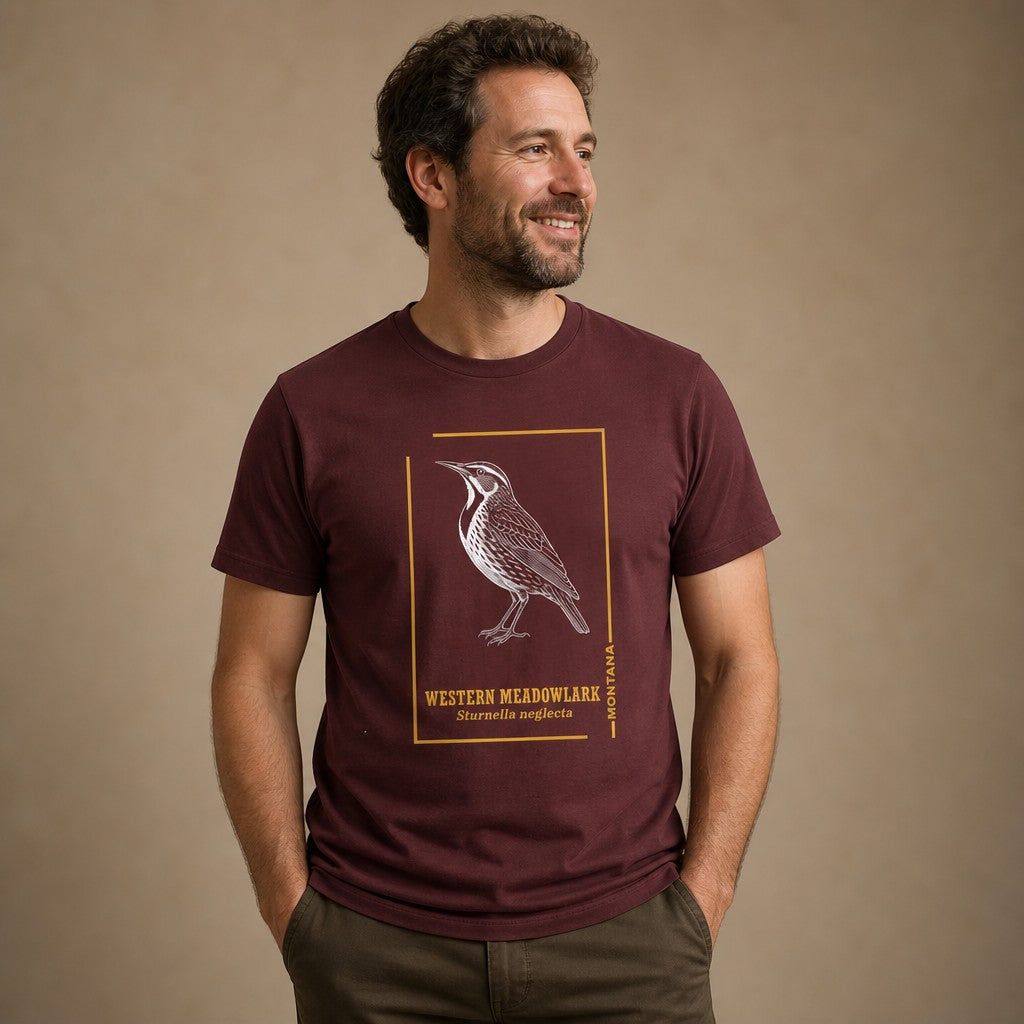 Man wearing a maroon Bella Canvas 3001 t-shirt featuring a hand-drawn vintage etching of a Western Meadowlark in crisp white ink, framed with golden lines and classic field guide typography, ideal for birdwatchers and heritage nature art lovers, by Crossroads Dandelion