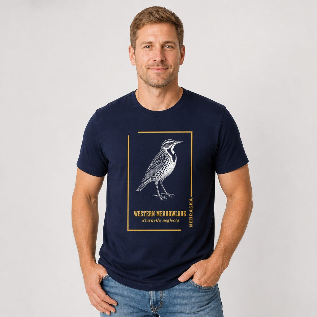 Man wearing a navy Bella Canvas 3001 t-shirt featuring a vintage hand-drawn Western Meadowlark illustration in white ink with golden accent lines and botanical typography, classic field guide style for birders and nature lovers, by Crossroads Dandelion