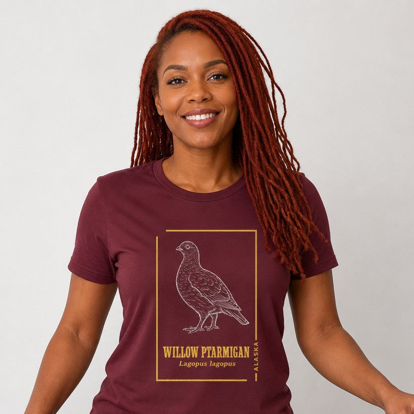 Woman in maroon Bella Canvas 3001 t-shirt featuring a vintage hand-drawn willow ptarmigan and golden botanical accents, Alaska state bird design, cottagecore style for birdwatchers and wildlife lovers, by Crossroads Dandelion