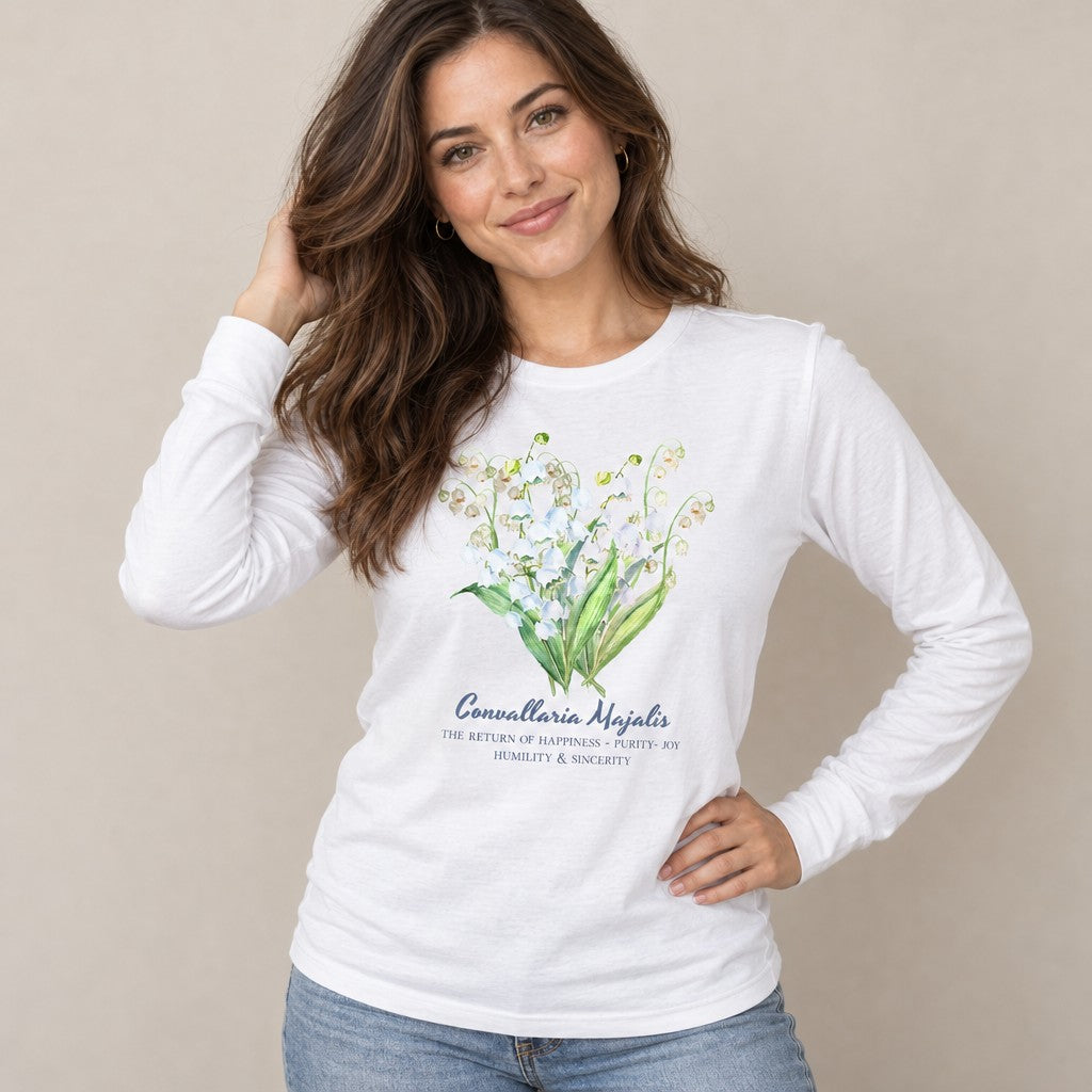 Woman wearing a white Bella Canvas 3501 long sleeve shirt with a delicate watercolor Convallaria Majalis (Lily of the Valley) floral design and elegant hand-lettered botanical text, vintage romantic botanical apparel for women, by Crossroads Dandelion
