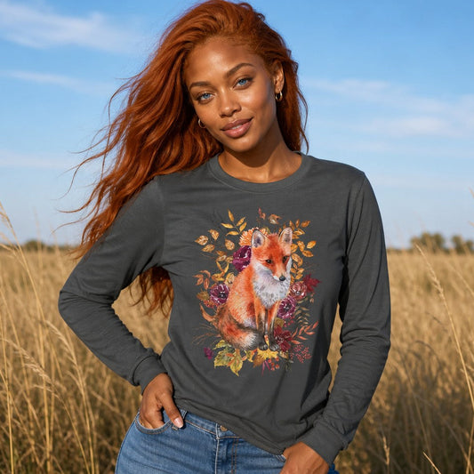 Woman wearing an asphalt grey Bella Canvas 3501 long sleeve shirt featuring a vivid watercolor red fox surrounded by plum and golden autumn botanical florals, cottagecore style, standing in a golden field, perfect for nature lovers and creative spirits, by Crossroads Dandelion
