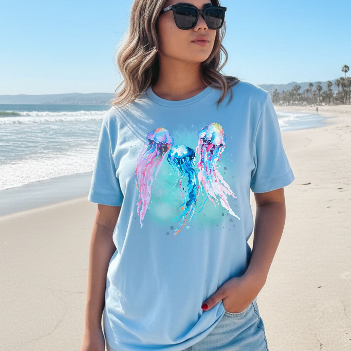 Woman wearing a baby blue t-shirt with jellyfish design on a beach