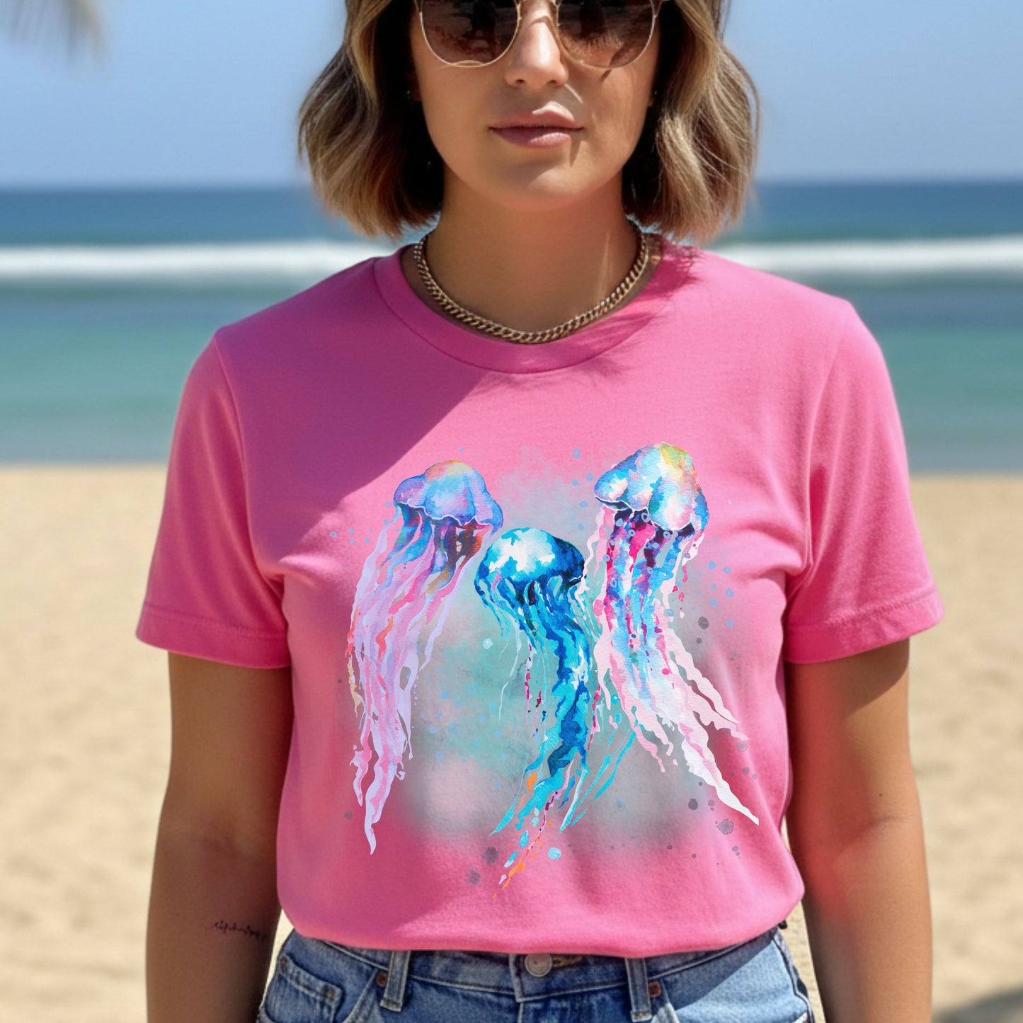 Person wearing a charity pink (pink) t-shirt with colorful jellyfish design on a beach