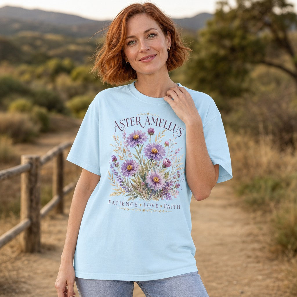 Woman wearing a chambray Comfort Colors 1717 t-shirt with a whimsical hand-painted watercolor Aster Amellus flower bouquet design, botanical art style, walking on a rustic nature path, ideal for garden lovers and nature enthusiasts, by Crossroads Dandelion