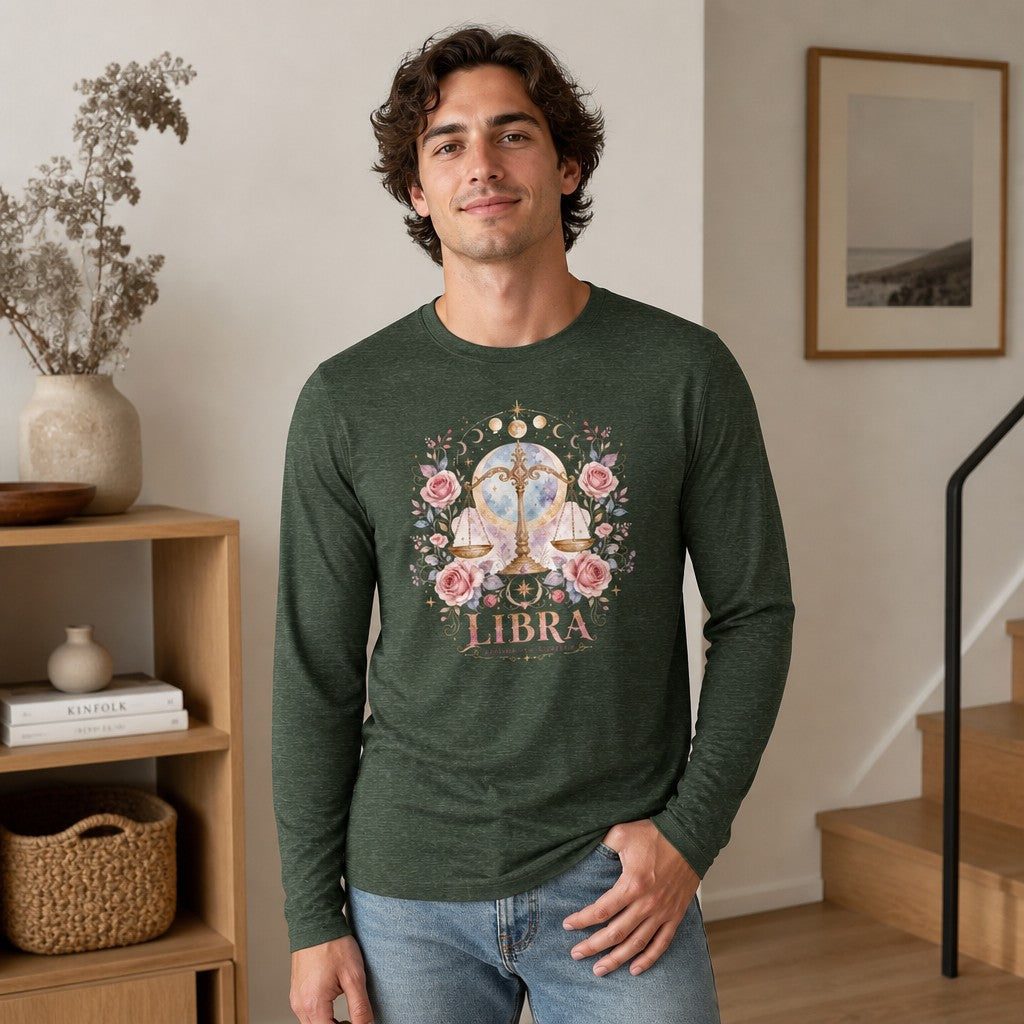 Man wearing heather forest long sleeve Bella Canvas 3501 featuring a whimsical watercolor Libra zodiac design with golden scales, pink roses, and celestial moon backdrop, styled for astrology lovers and fans of poetic vintage nature art, indoors in a modern home, by Crossroads Dandelion