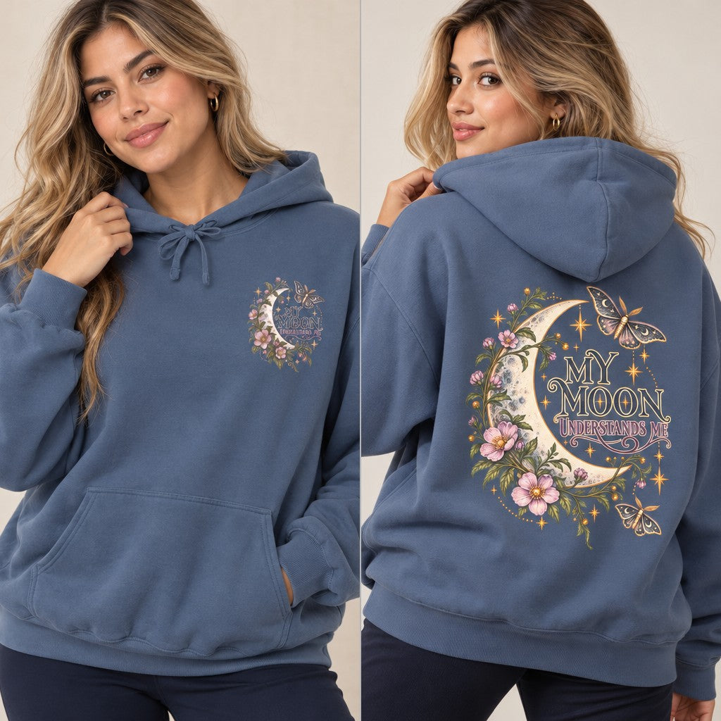 Woman wearing a denim blue hoodie featuring a whimsical crescent moon, florals, and moths design with the phrase 'My Moon Understands Me,' cozy casual style, ideal for lunar enthusiasts and nature lovers, by Crossroads Dandelion