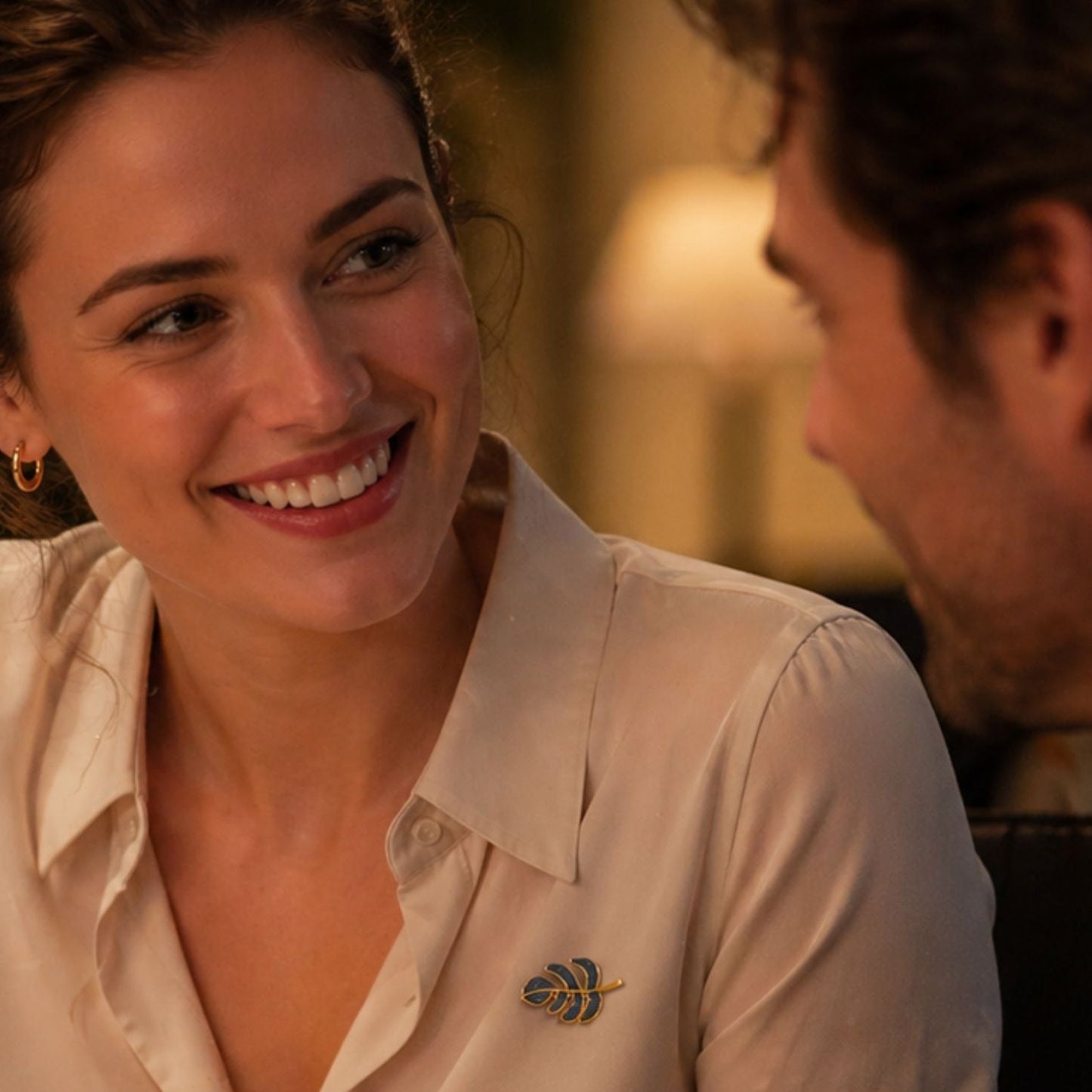Elegant woman wearing leaf brooch during dinner conversation, by Crossroads Dandelion