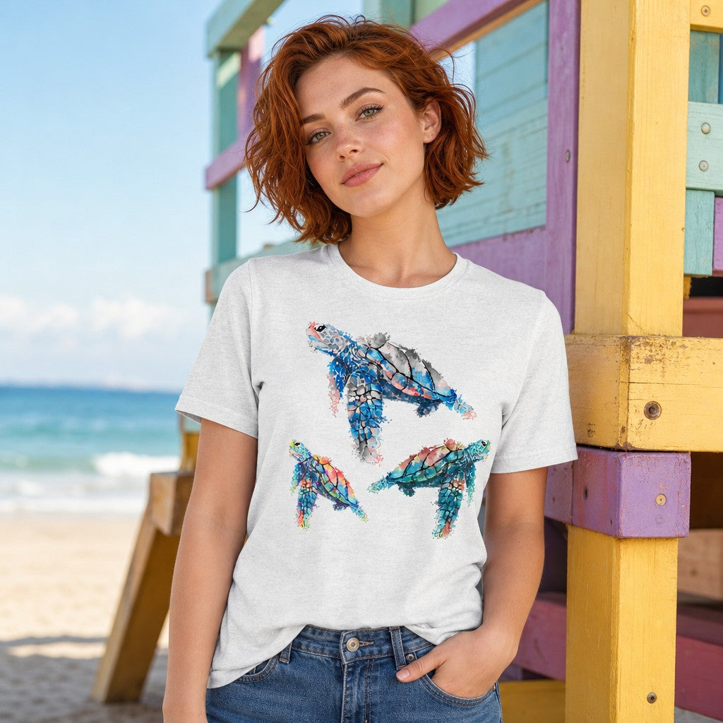 Woman wearing ash Bella Canvas 3001 t-shirt featuring dreamy watercolor abstract sea turtles design, standing by colorful beach hut on sandy shore, by Crossroads Dandelion