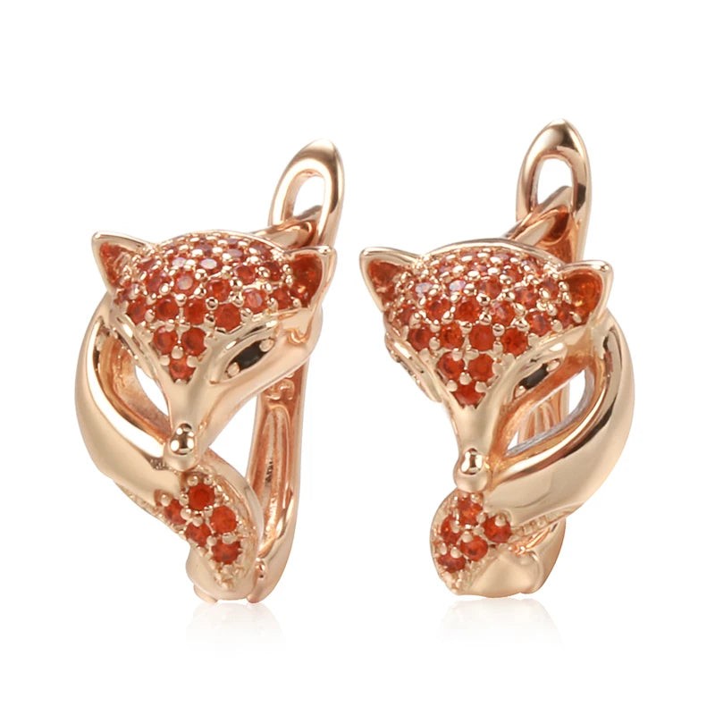 Pair of rose gold fox earrings with red cubic zirconia, front view on white