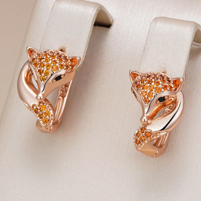 Rose gold fox earrings with orange-red stones displayed on cream satin loops