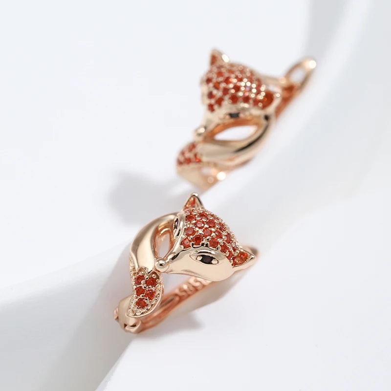 Close-up of rose gold fox earrings showing the pavé red stones and curled tail