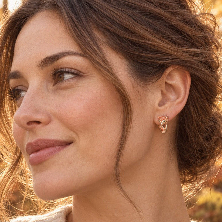 Woman in a cream knit sweater wearing a rose gold fox earring in an autumn woodland